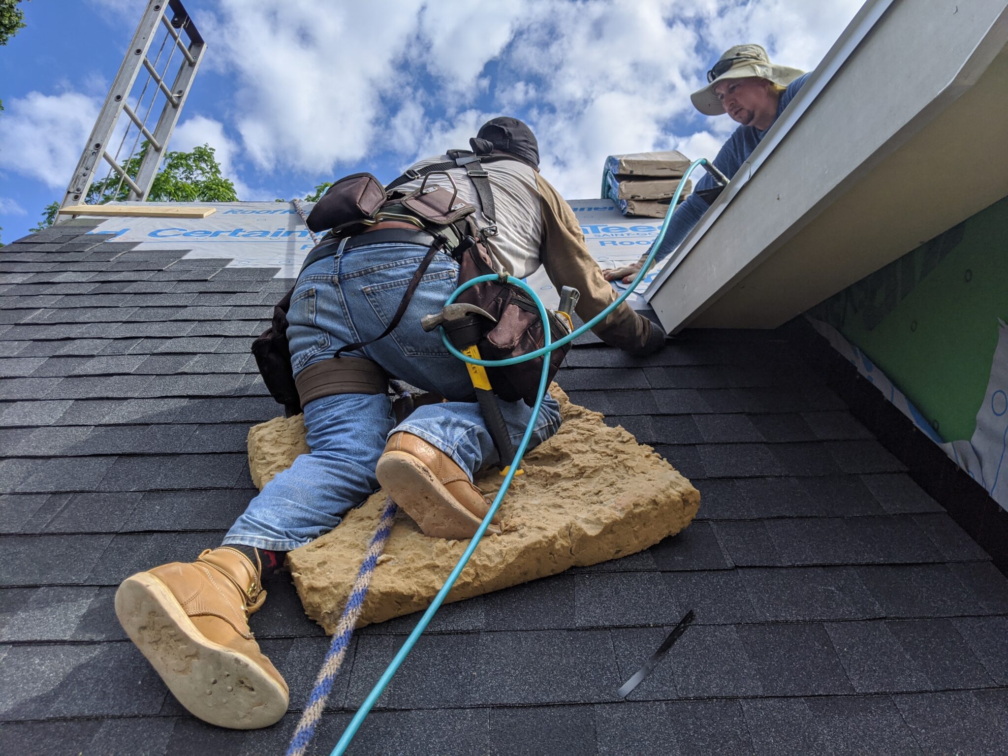 Roofer repairing shingles on a residential roof